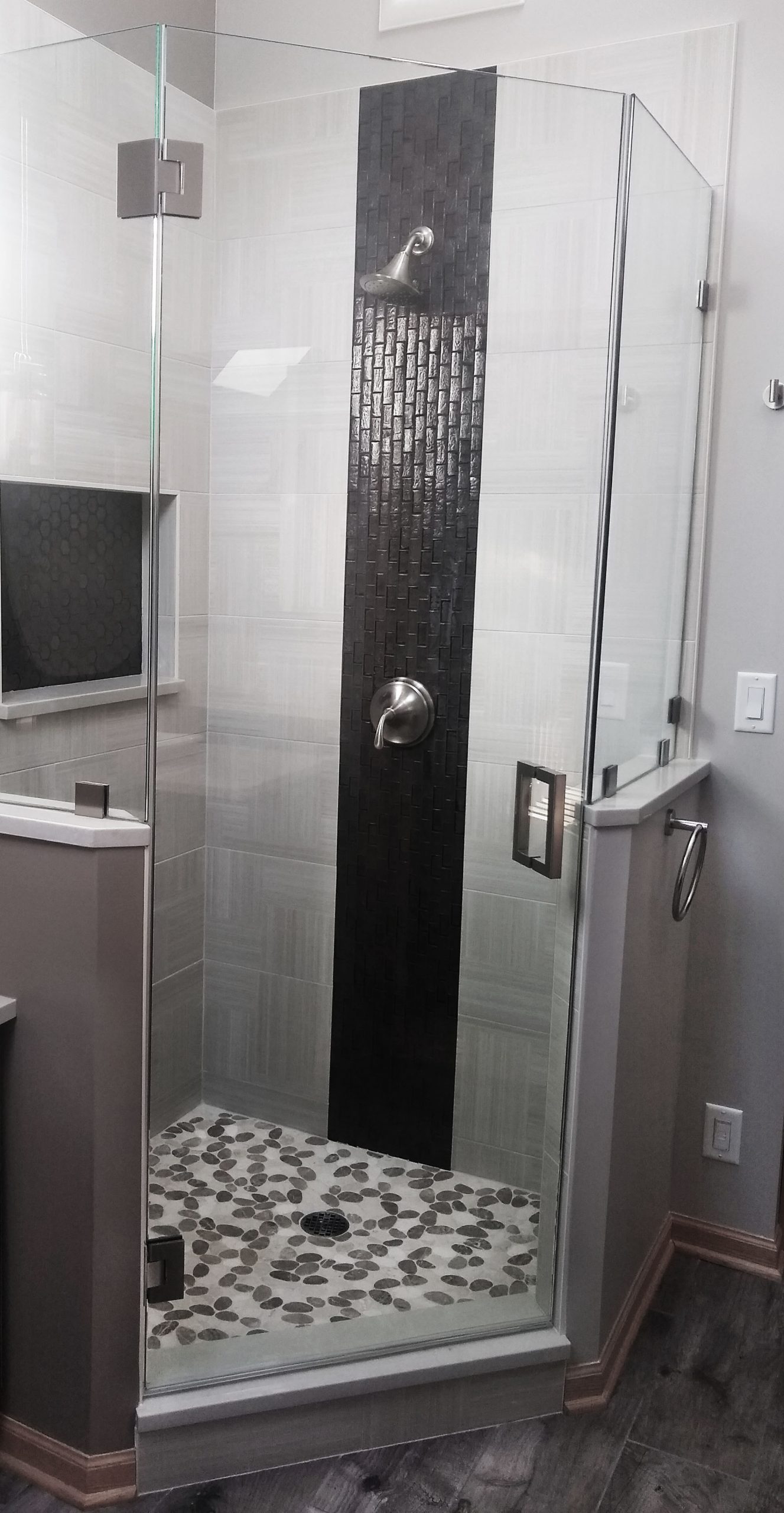 Shower with glass enclosure, half wall, and vertical accent tile