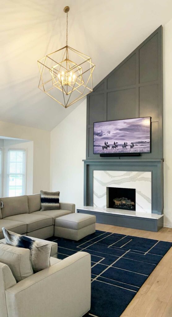 white fireplace on asymmetrical wall with gray moulding and TV above