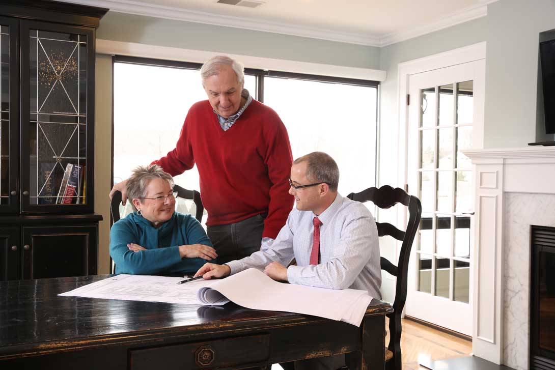 Husband and wife looking at blueprints with their architect