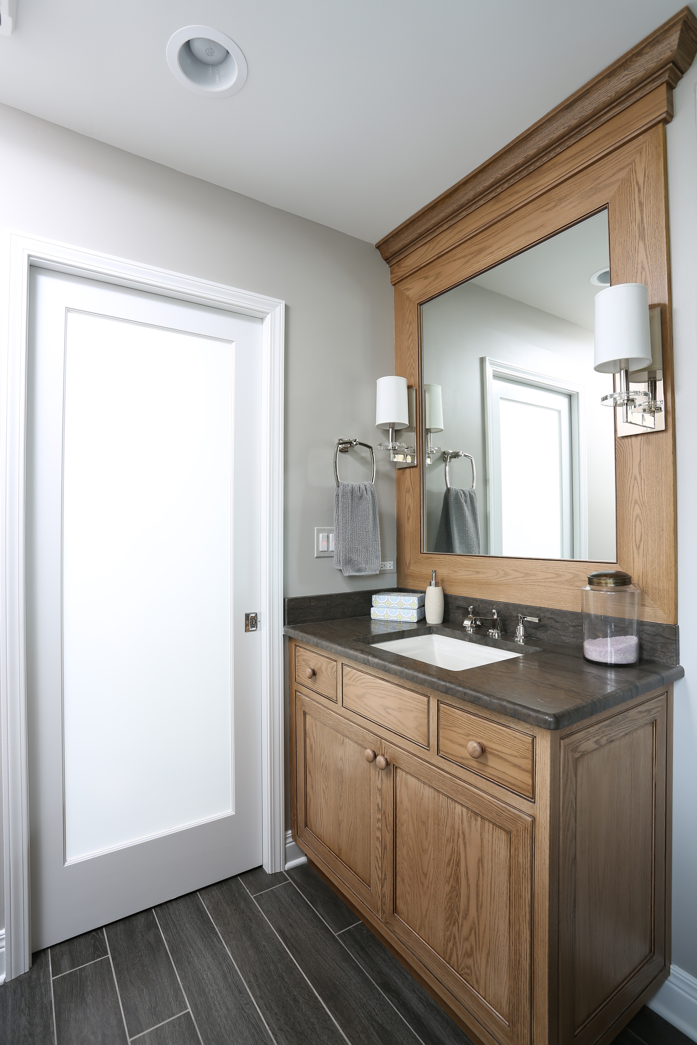 Separate vanities in a primary bathroom with stained cabinetry