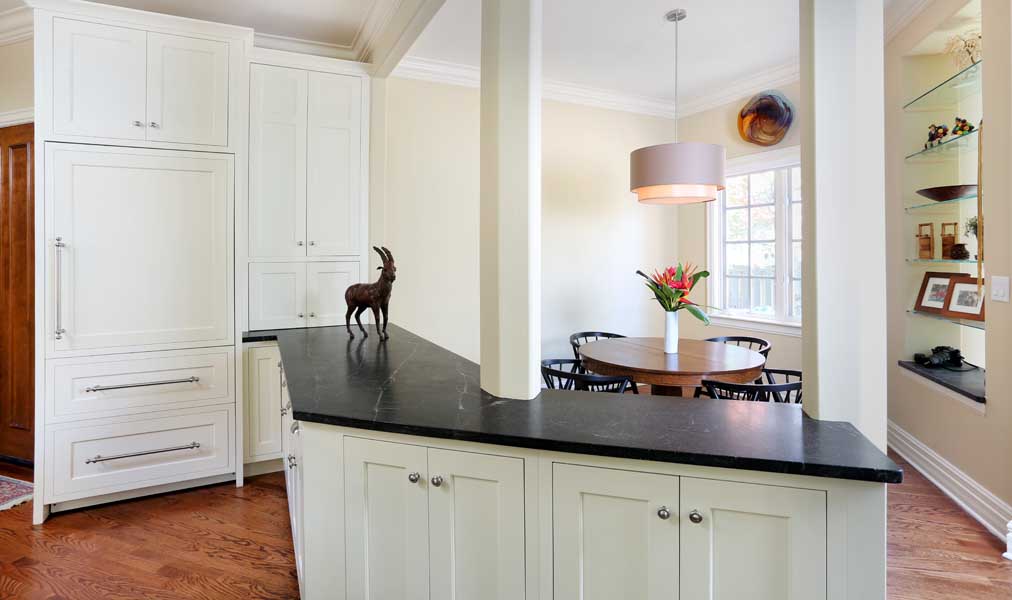 Casual dining space separated by columns and cabinets from kitchen