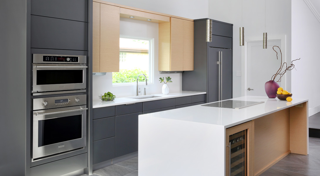 Multi tone kitchen with cooktop in the island and wall ovens