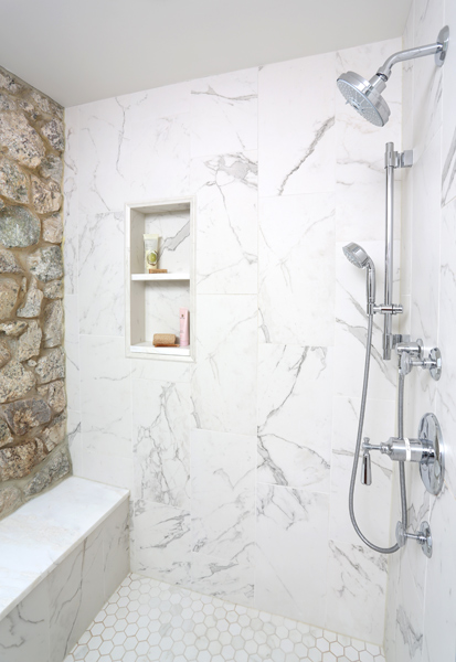 master shower with marble look tile and exposed stone