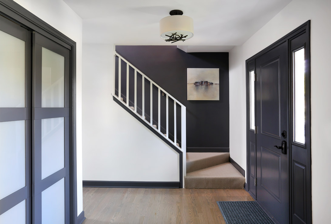 foyer with square spindles on the stair railing and three panel doors on the entry closet