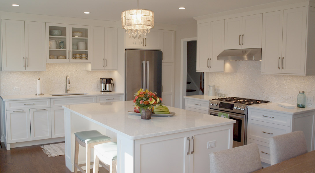 L shaped kitchen with island in white cabinetry with white countertops