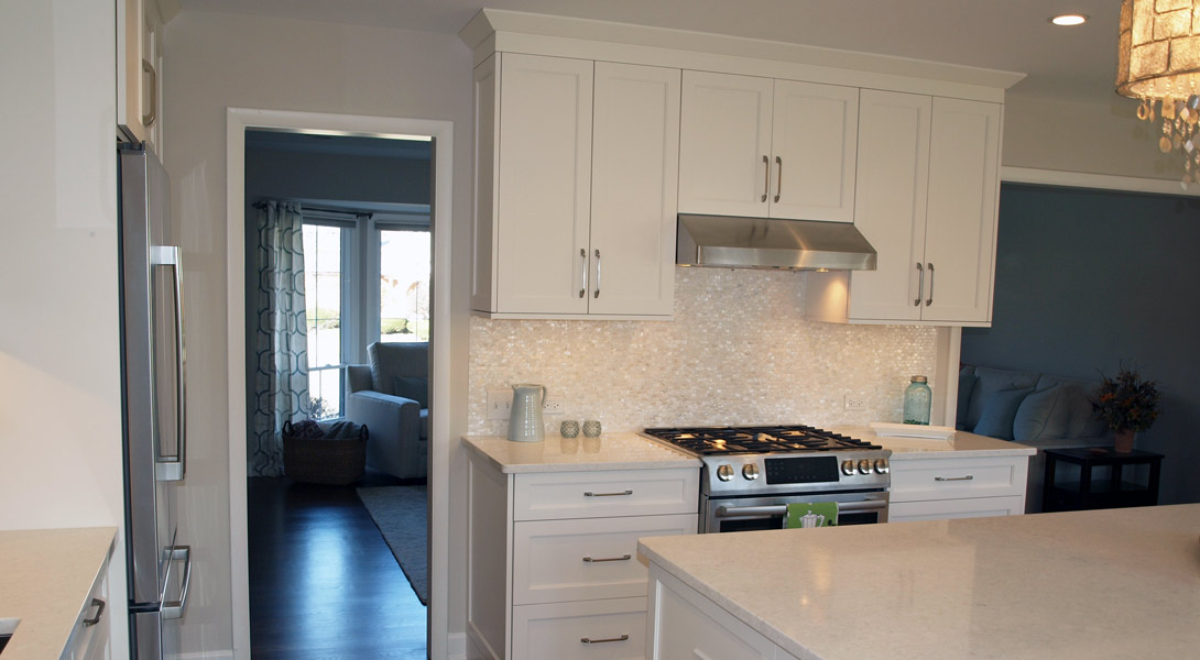 White kitchen cabinetry with a metal hood