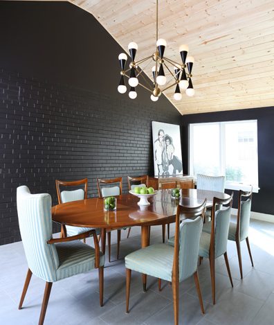 dining room with black painted brick wall and natural exposed wood ceiling