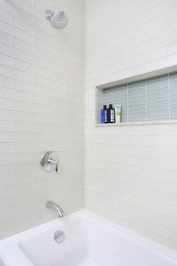 bathtub and shower combination with a colorful tile storage niche