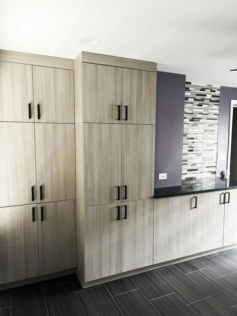 modern mudroom with locker style storage, purple walls, glass black and gray backsplash and gray flooring