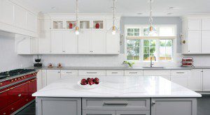 White kitchen cabinets with gray island and red range