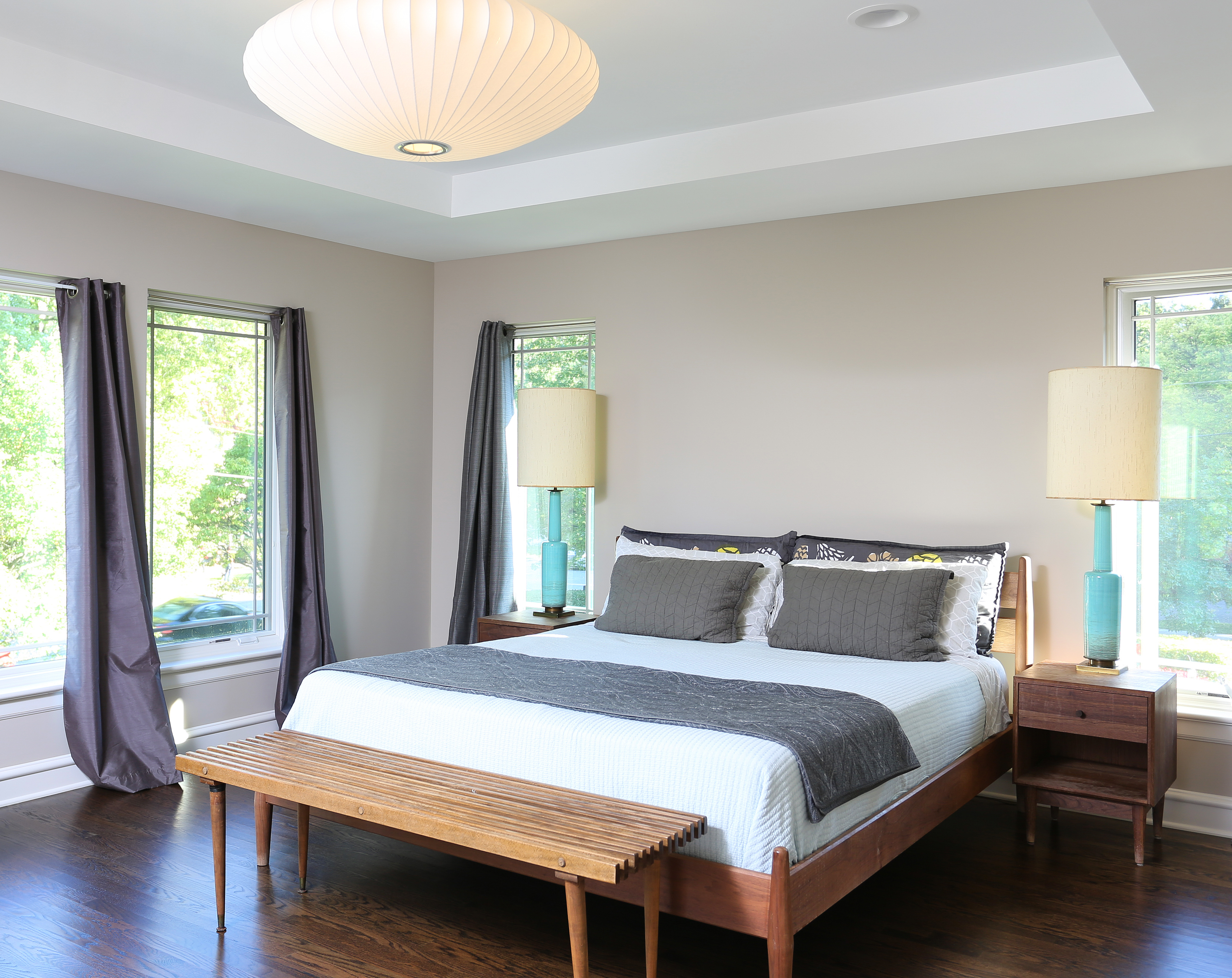 primary suite with layered lighting and bench at foot of bed