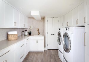 White laundry room cabinets with gold tone fixtures