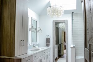 Remodeled bathroom with 2 bowl vanity, large shower with bench and tall cabinets for storage