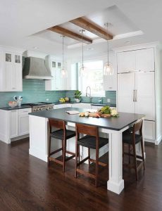 White kitchen cabinets with reclaimed wood beam ceiling and metal hood