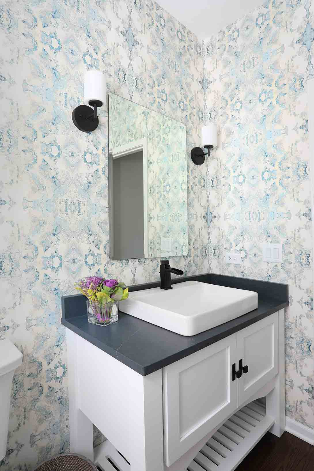 Drop in sink with dark stone top and white cabinet in a powder room