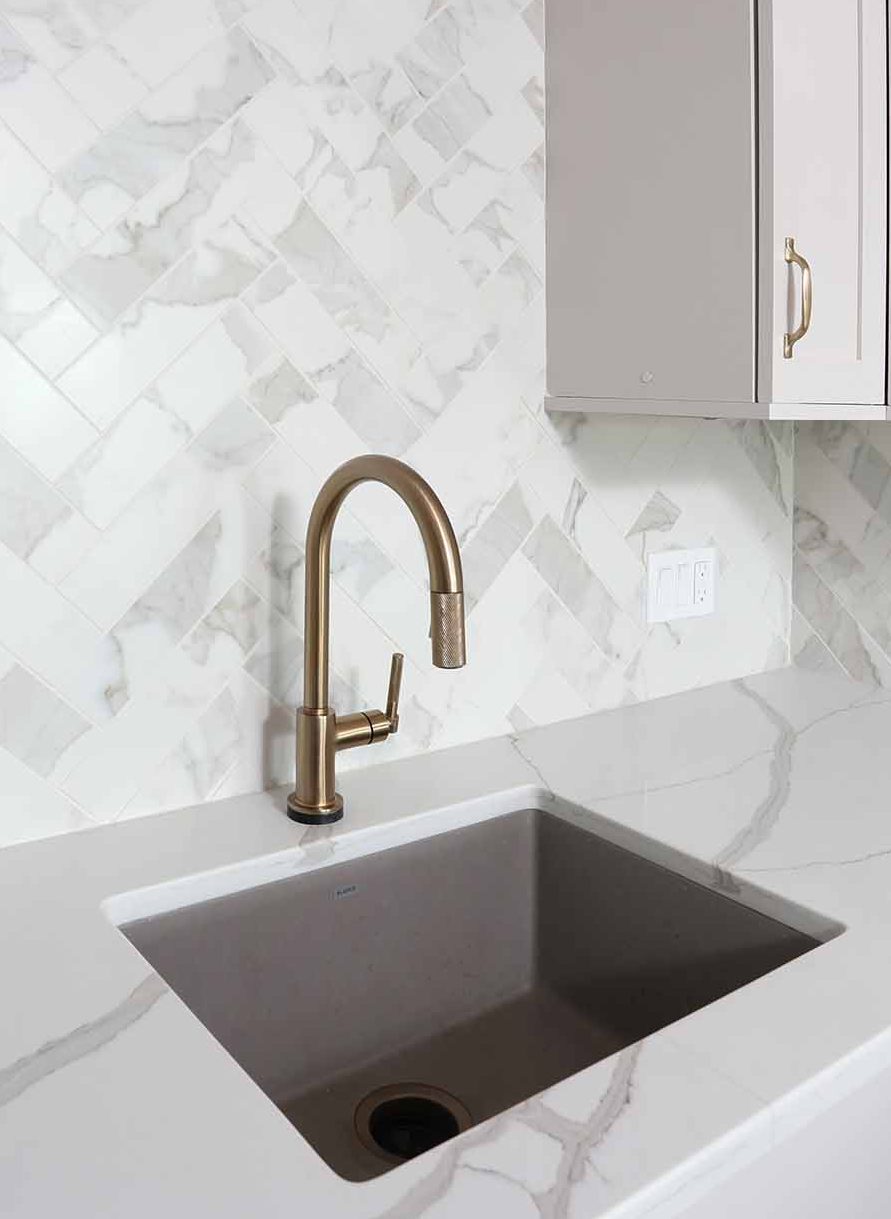 Marble-look porcelain tile backsplash to the ceiling, brass faucet, brass light fixture