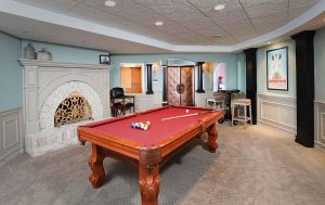 Large gaming room in basement with pool table fireplace, columns