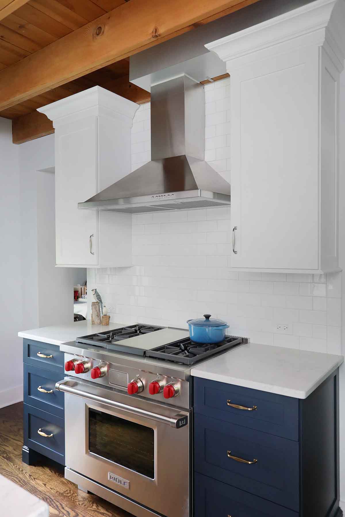 range flanked by upper and lower cabinets and metal hood