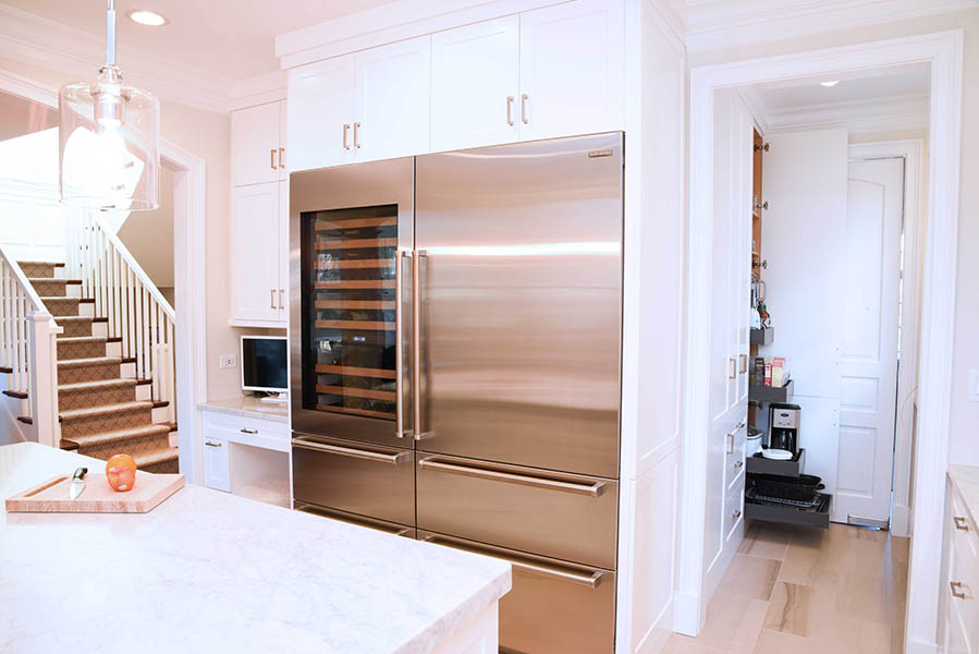 White painted kitchen cabinets with island and large refrigerator freezer as kitchen appliances