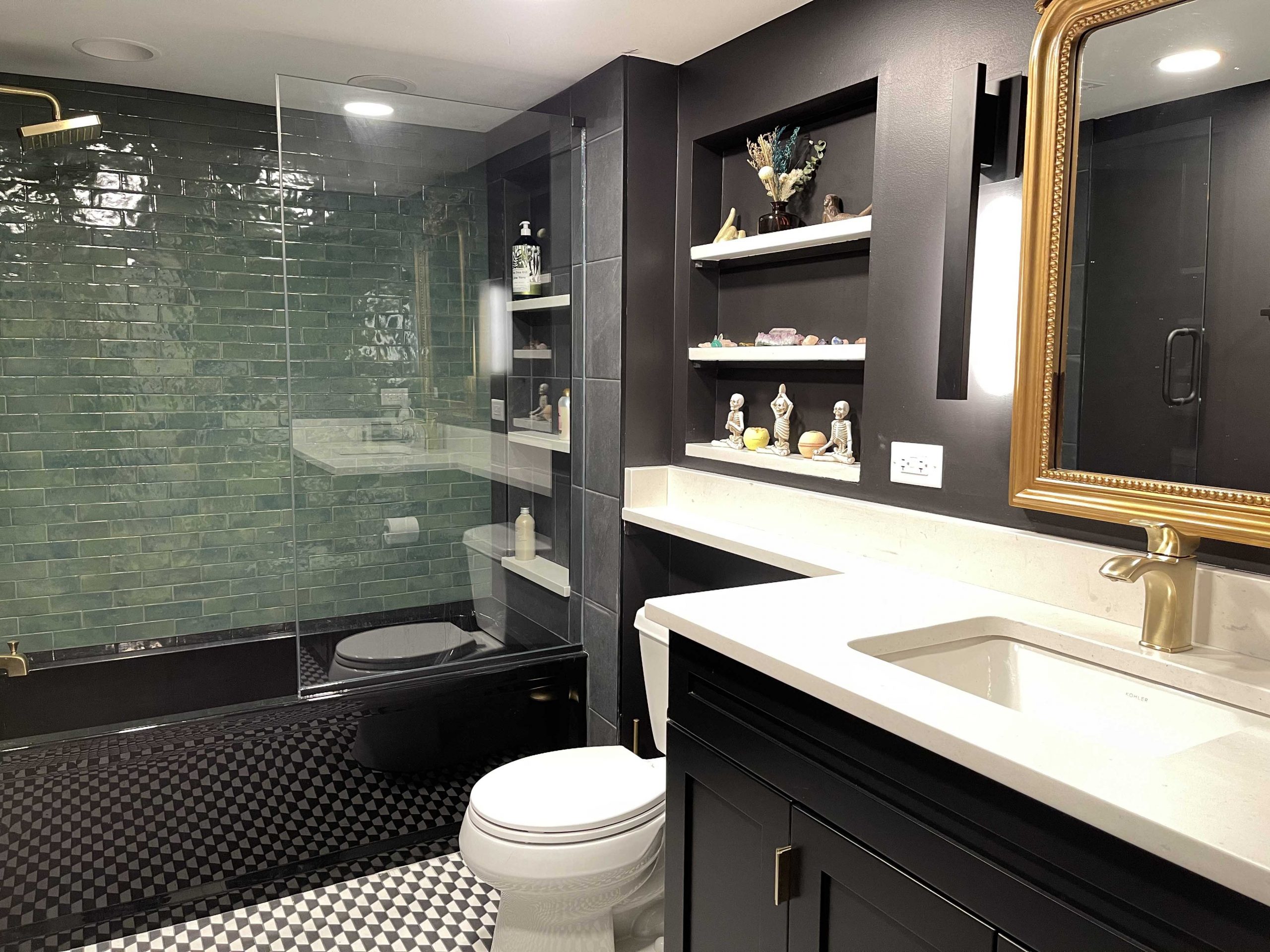 Black bathroom cabinetry and bathtub with banjo countertop and green tile wall with gold accents