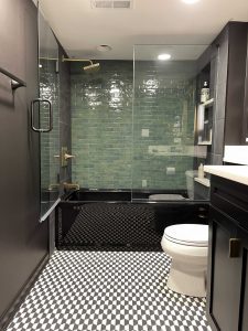 Emerald green accent tile wall in a black bathroom