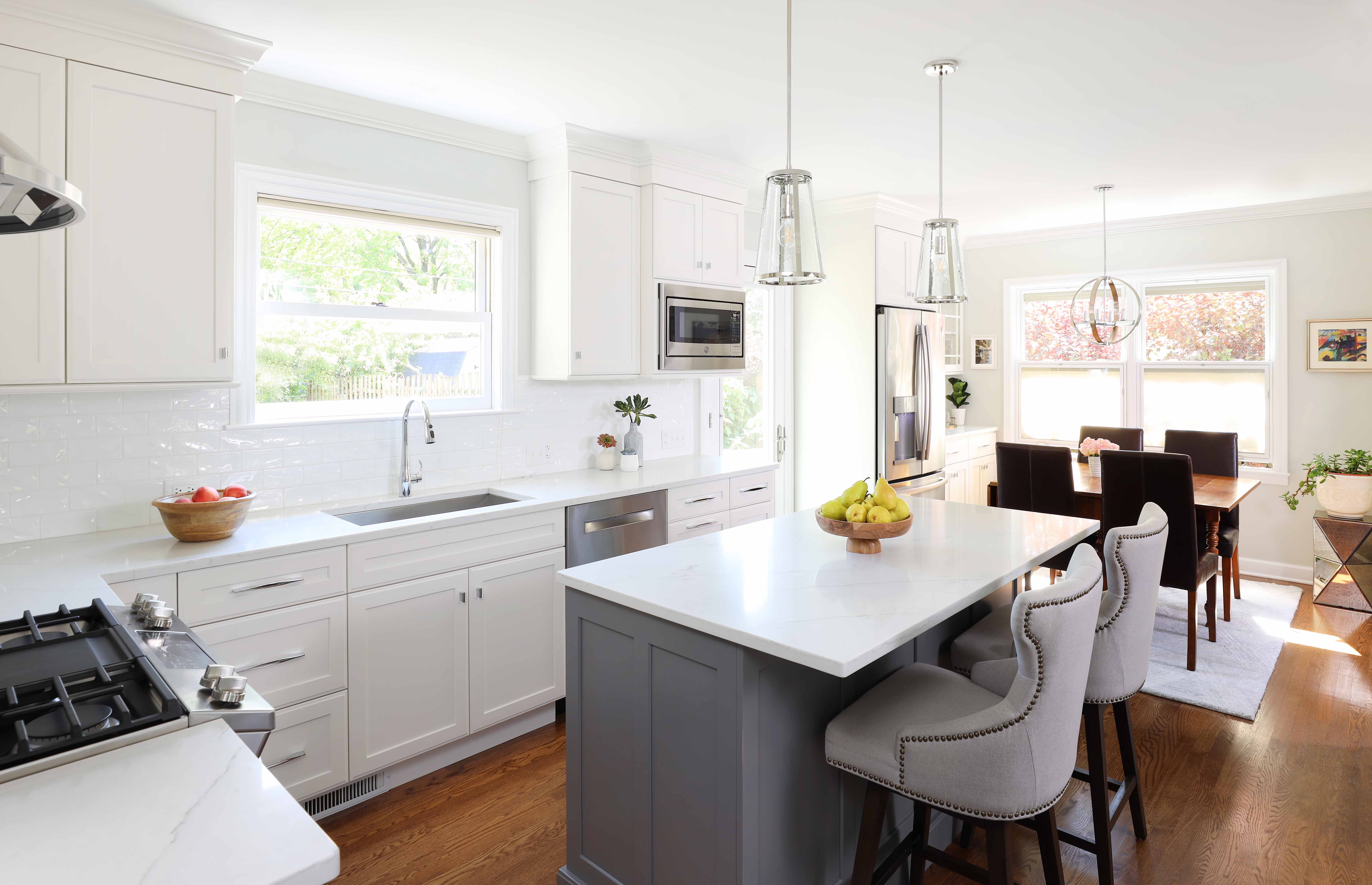 Open concept white kitchen cabinets with gray island cabinets