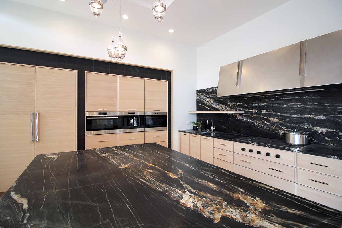 Modern kitchen with light wood cabinets and dark stone countertop