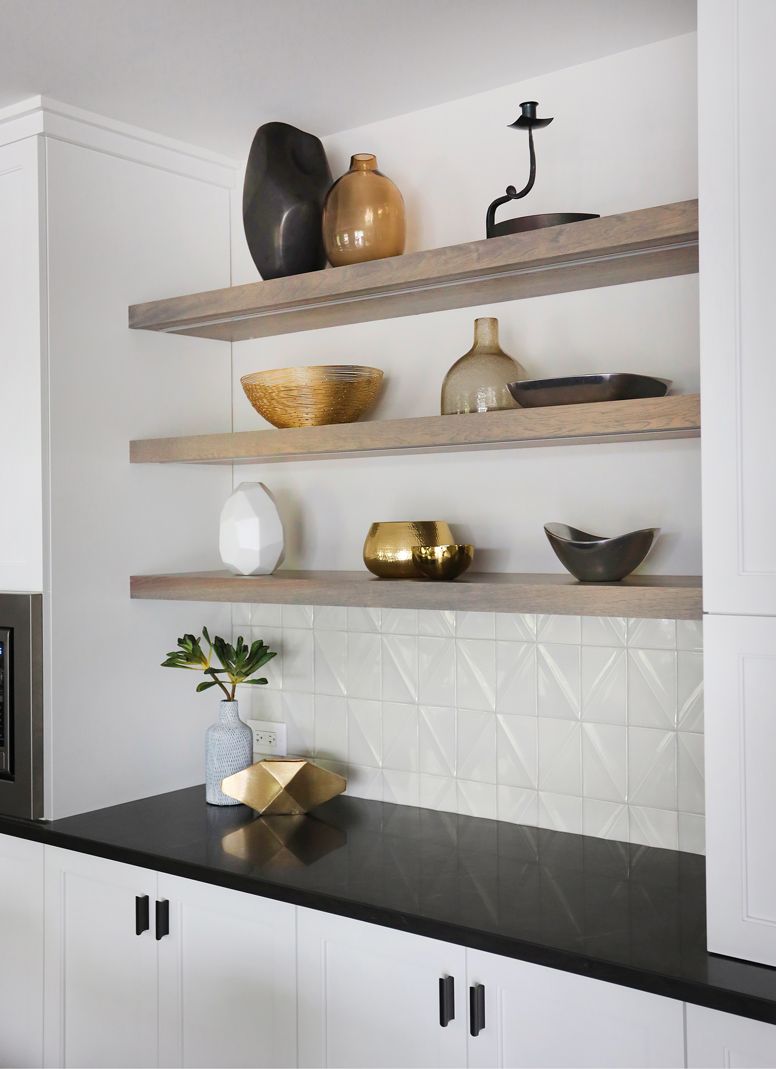 Open shelving above textured tile in the kitchen