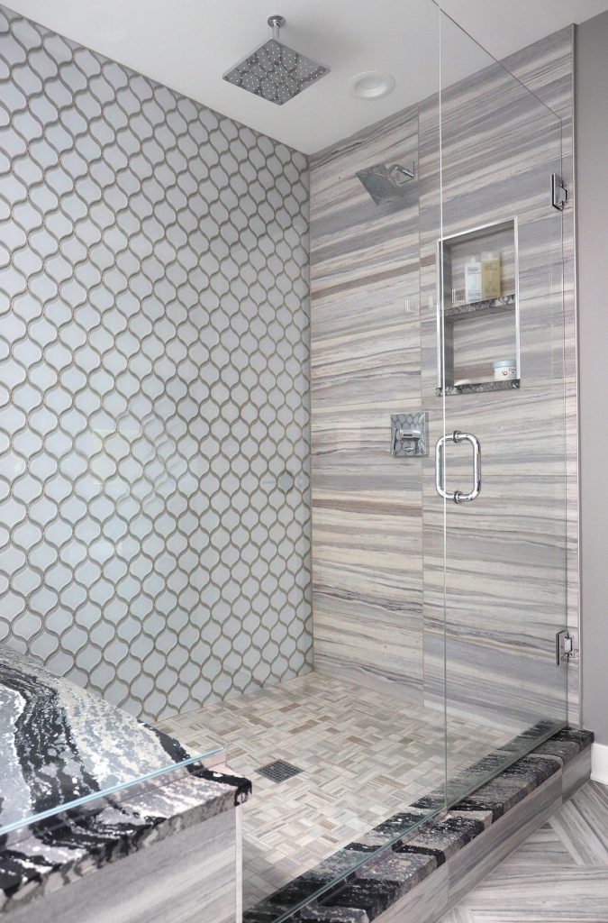 framless shower with 3 types of patterned tile on walls and shower floor, with niche and rain showerhead