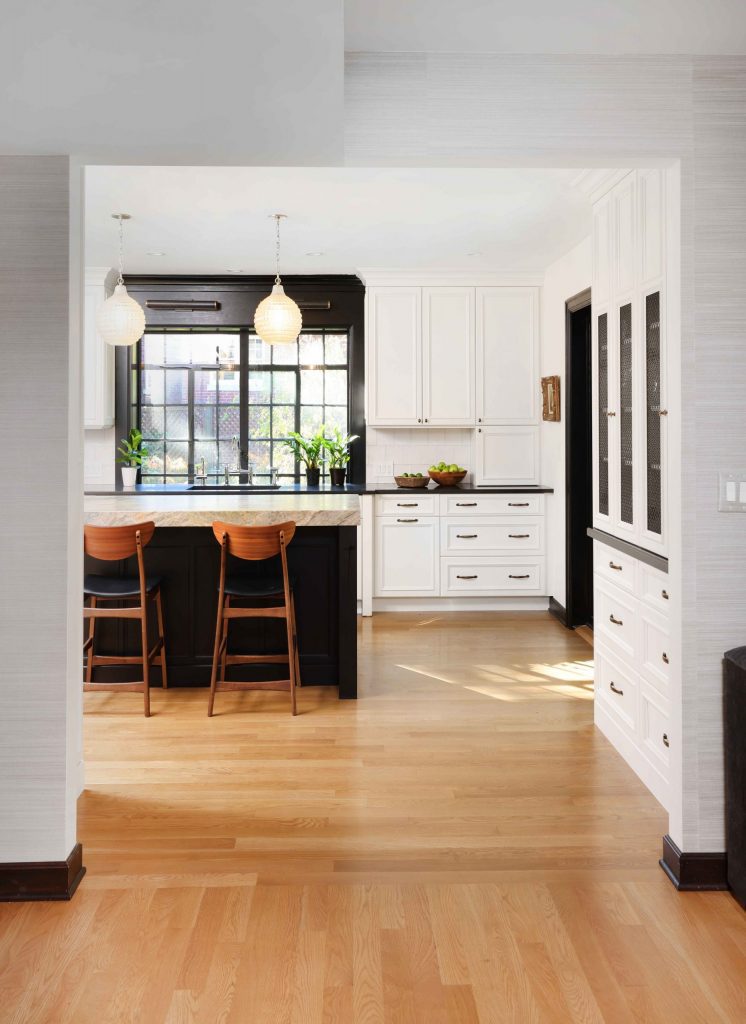 hardwood flooring in white kitchen with dark island and black window