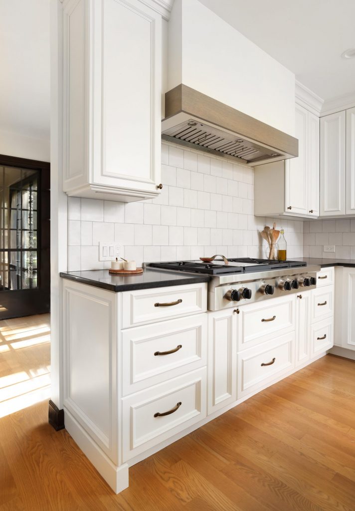 wood hood with contrasting band in white kitchen with dark countertops