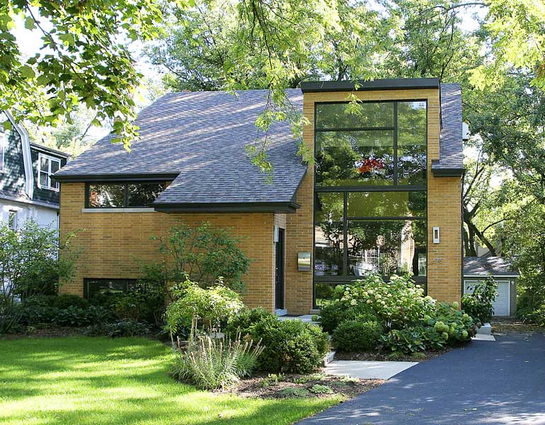 Modern home exterior featuring a wall of windows and a butterfly roof