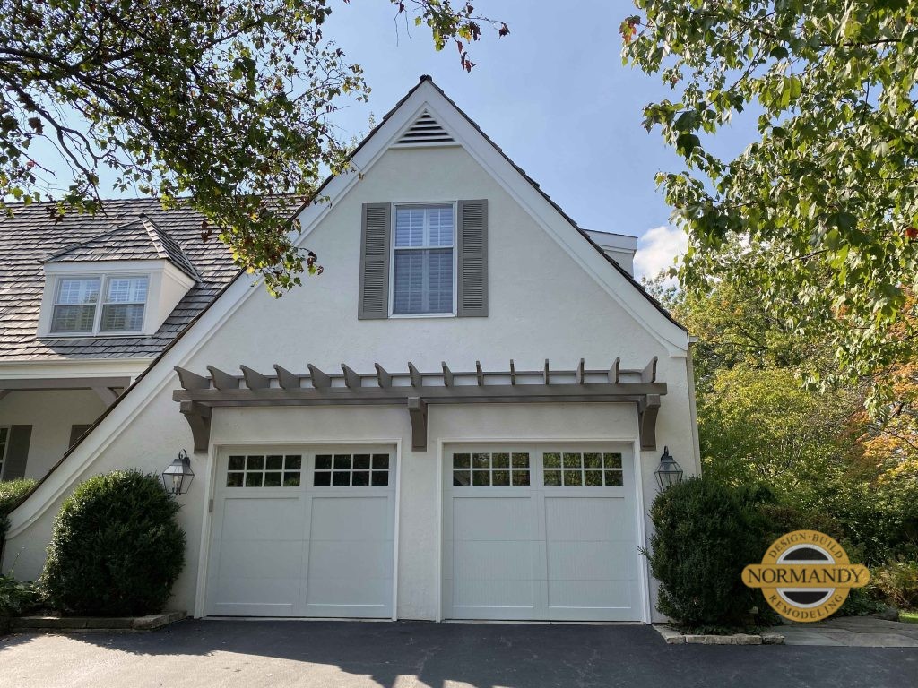 Attached garage with a decorative eyebrow pergola above the doors