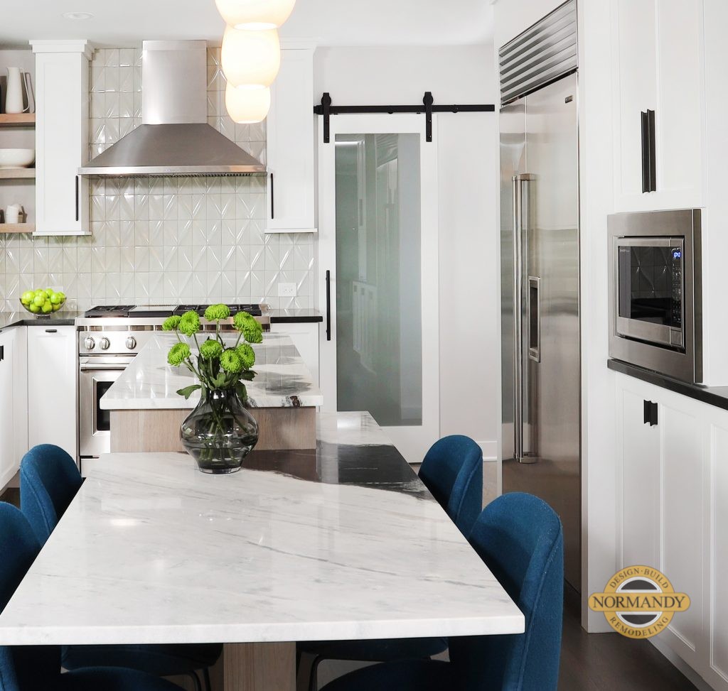 White kitchen with two tier island and barn door over pantry