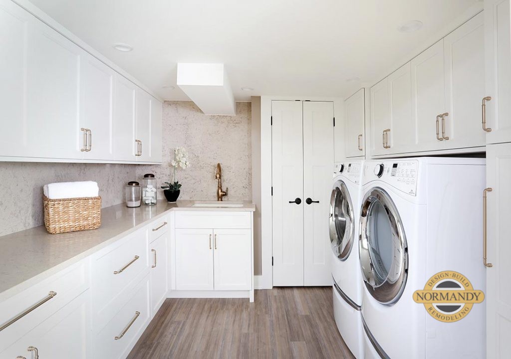 White laundry room cabinets with gold tone fixtures