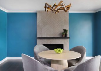 Table and chairs in lounge area with bright blue walls and texture tile fireplace