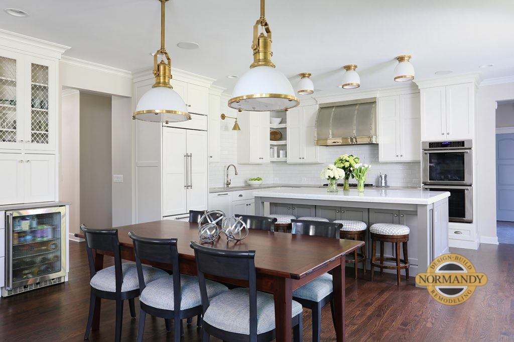 White and gray kitchen with stained table and pendants above