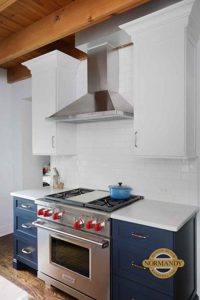 range flanked by upper and lower cabinets and metal hood