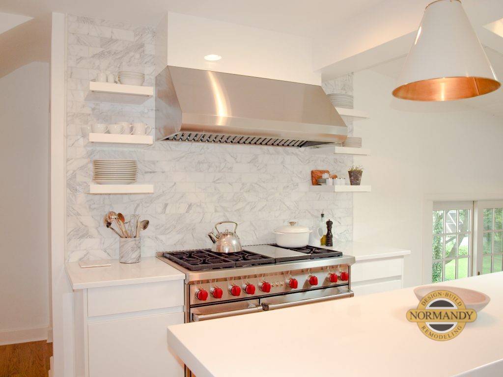 White kitchen with floating shelves over a slab backsplash