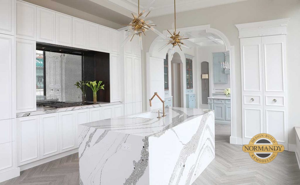 White kitchen cabinets with waterfall wrapped island in natural stone