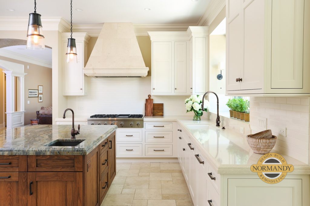 White kitchen cabinets with a stained island and stone hood