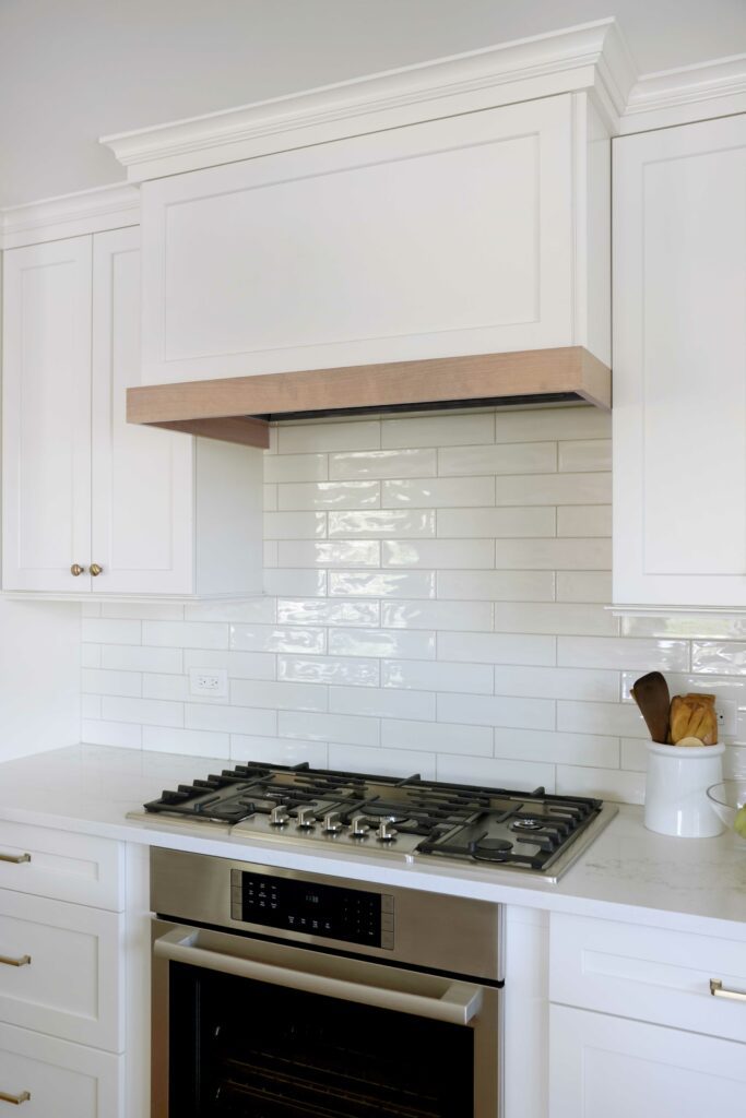 White kitchen with painted white wood hood and stained wood accents