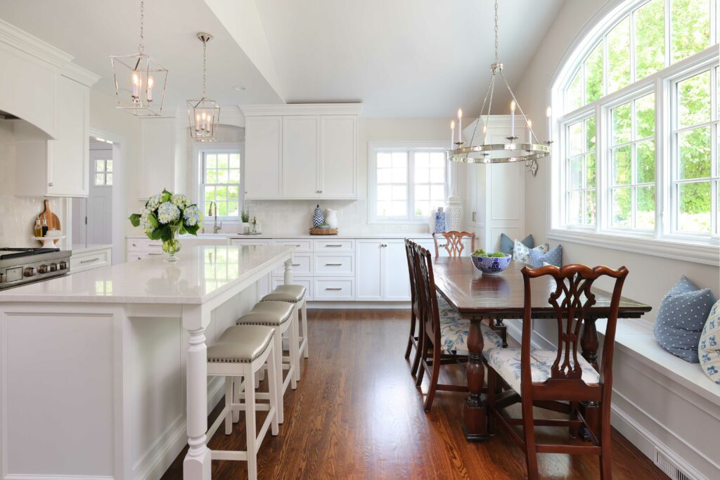 white kitchen addition with large island and stools and dining table with window bench seating