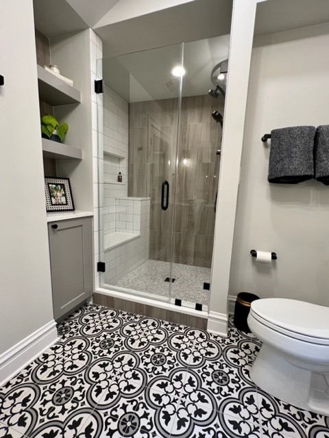 stand alone shower with wood wall look and decorative floor tile in black and white, open shelving in nook