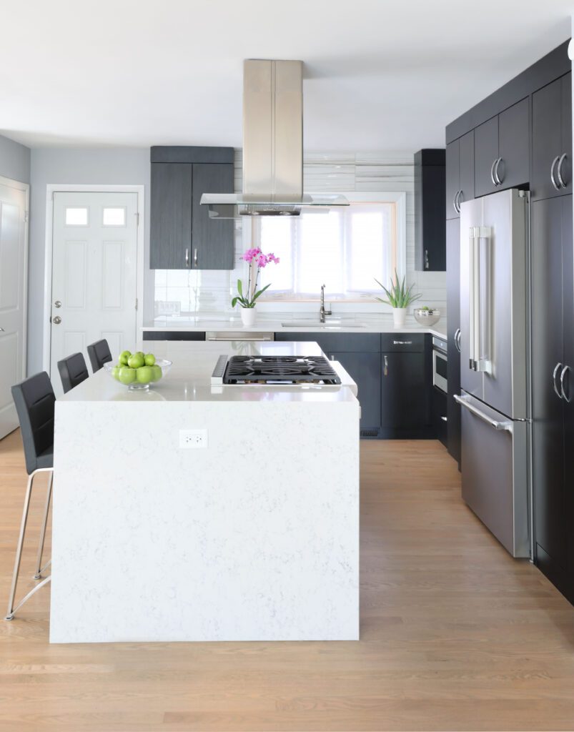 Modern kitchen with black slab cabinets and white waterfall countertop