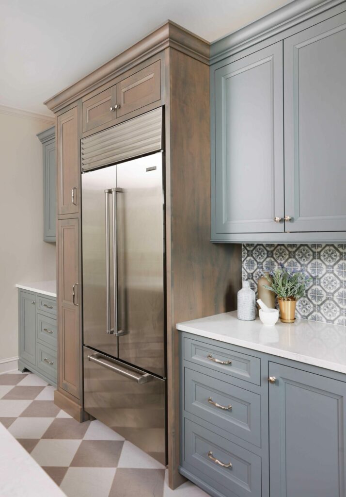 Stainless refrigerator with gray painted and stained wood cabinets and a checkerboard floor