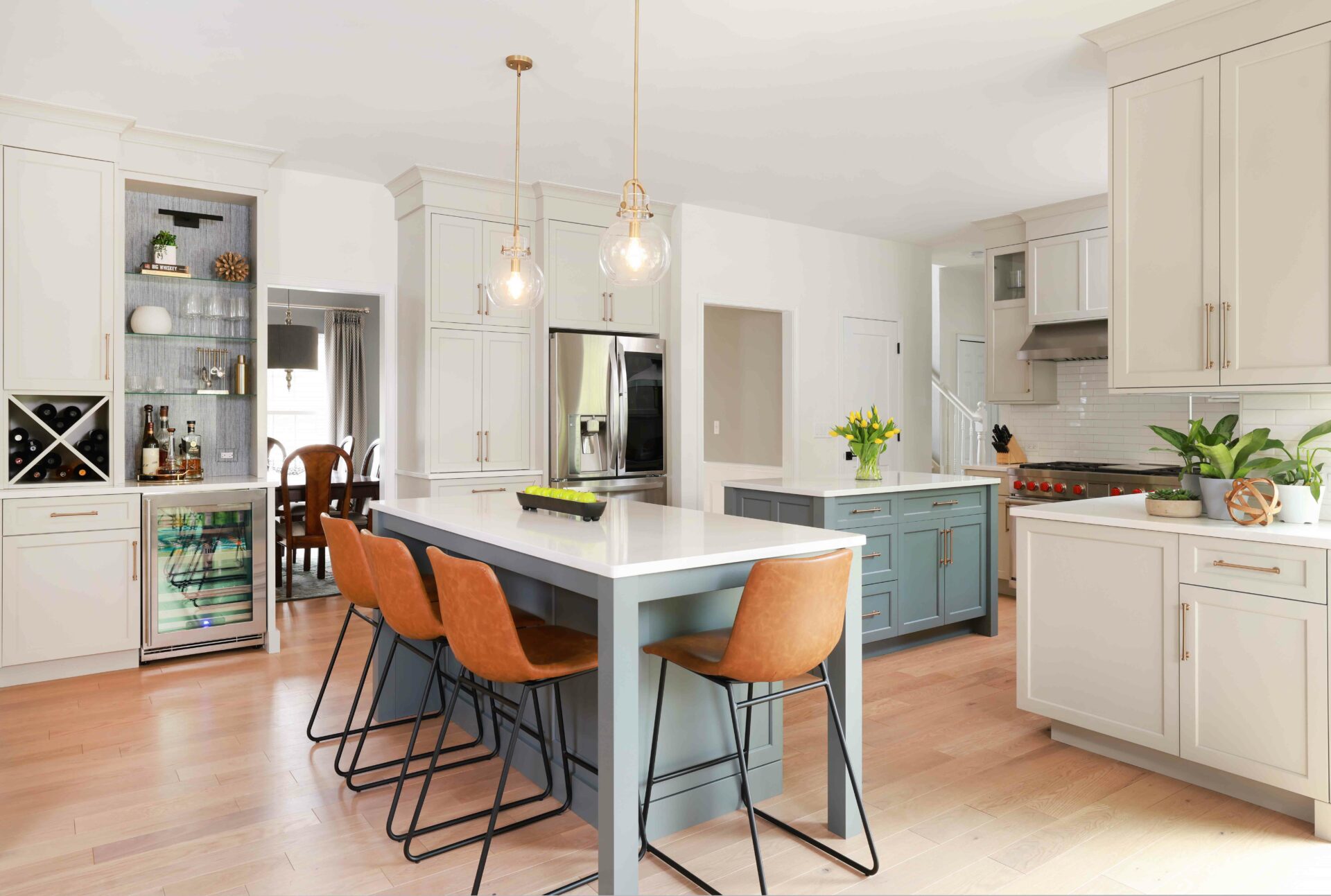 Warm white kitchen with two gray islands and home bar