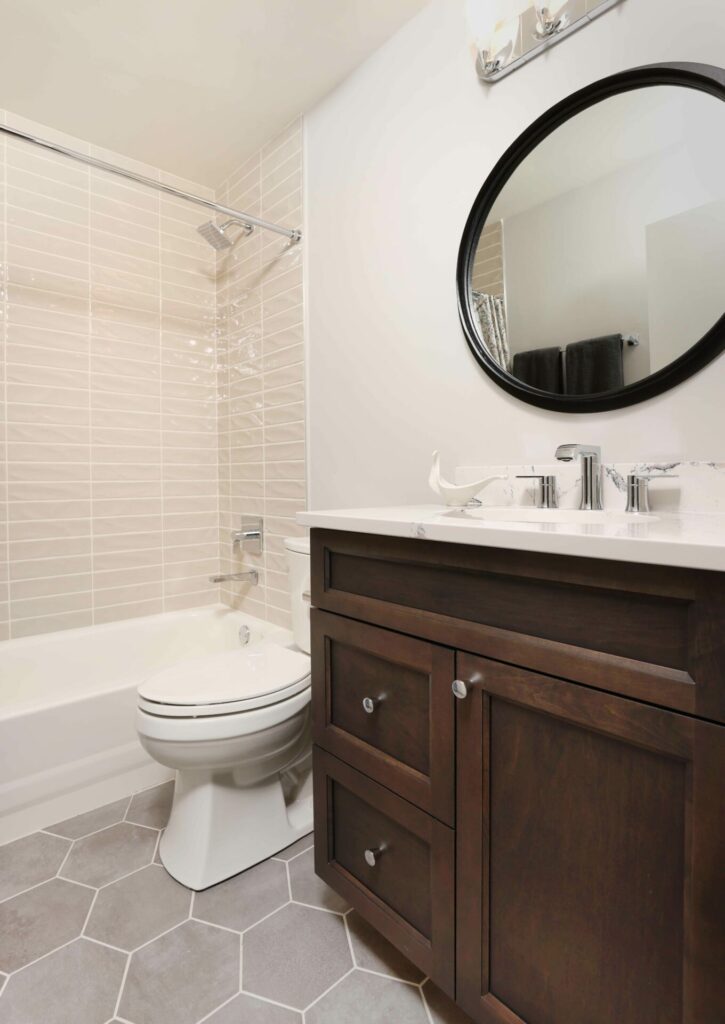 bathroom with dark cabinetry and hexagon floor tiles and horizontal tile in tub