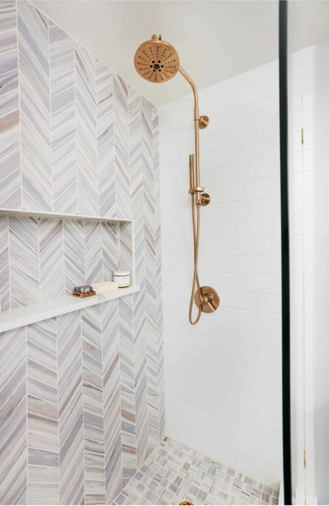 chevron tile in shower with niche and gold shower fixture