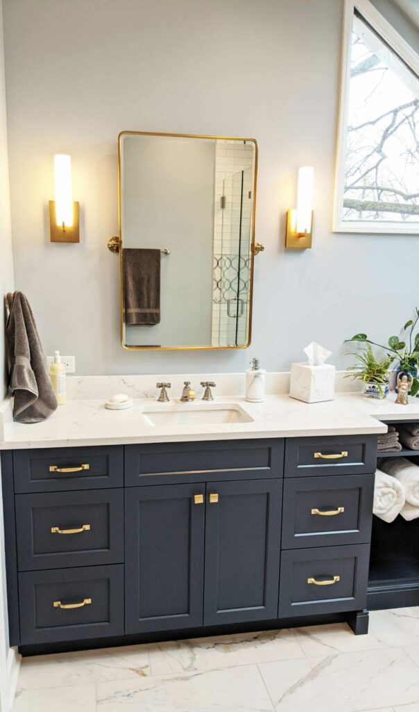 navy vanity with gold hardware and gold mirror with wall sconces